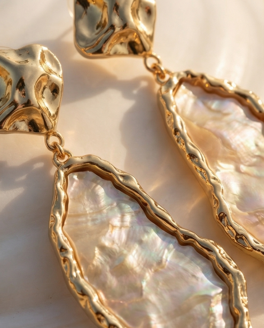Gold-framed pearl earrings on a light background