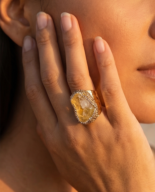 Close-up of a hand wearing a large, ornate ring with a prominent gemstone.