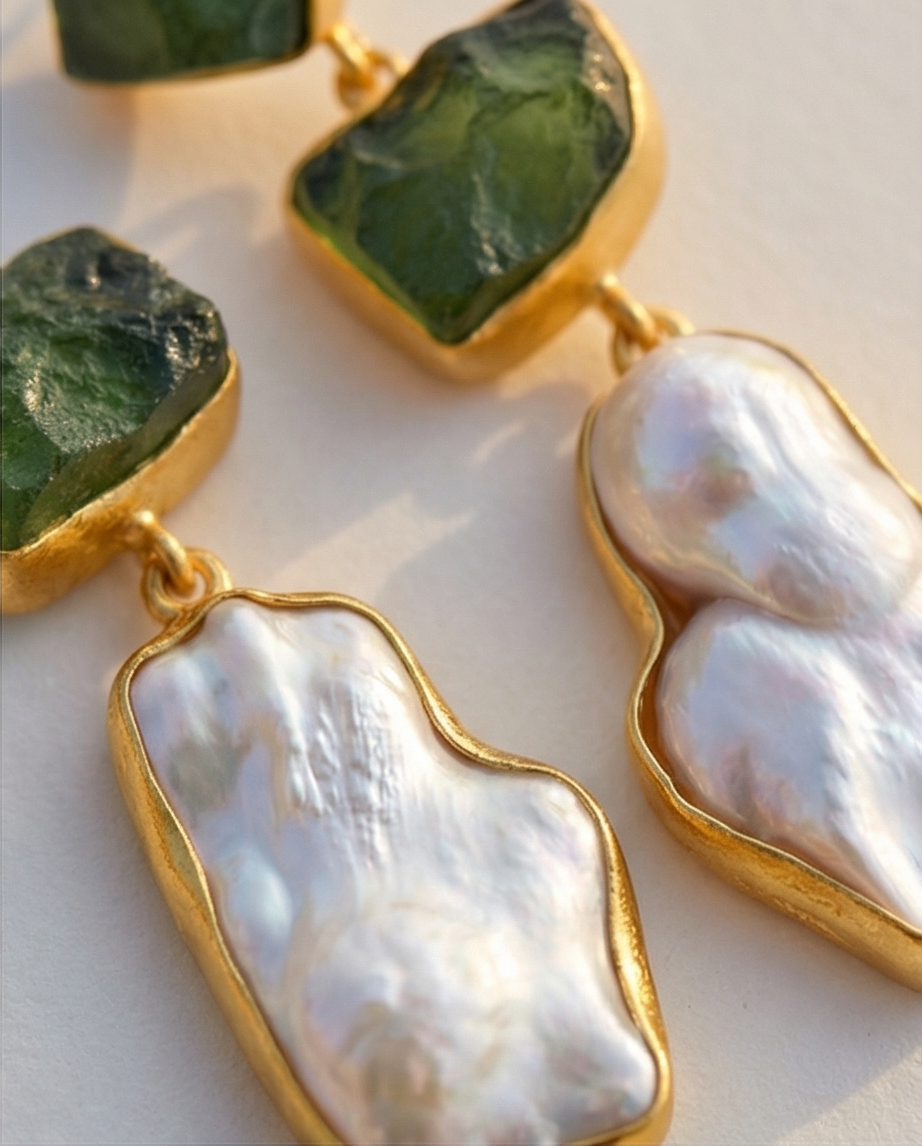Earrings with green stone and pearl-like gold accents on a light background